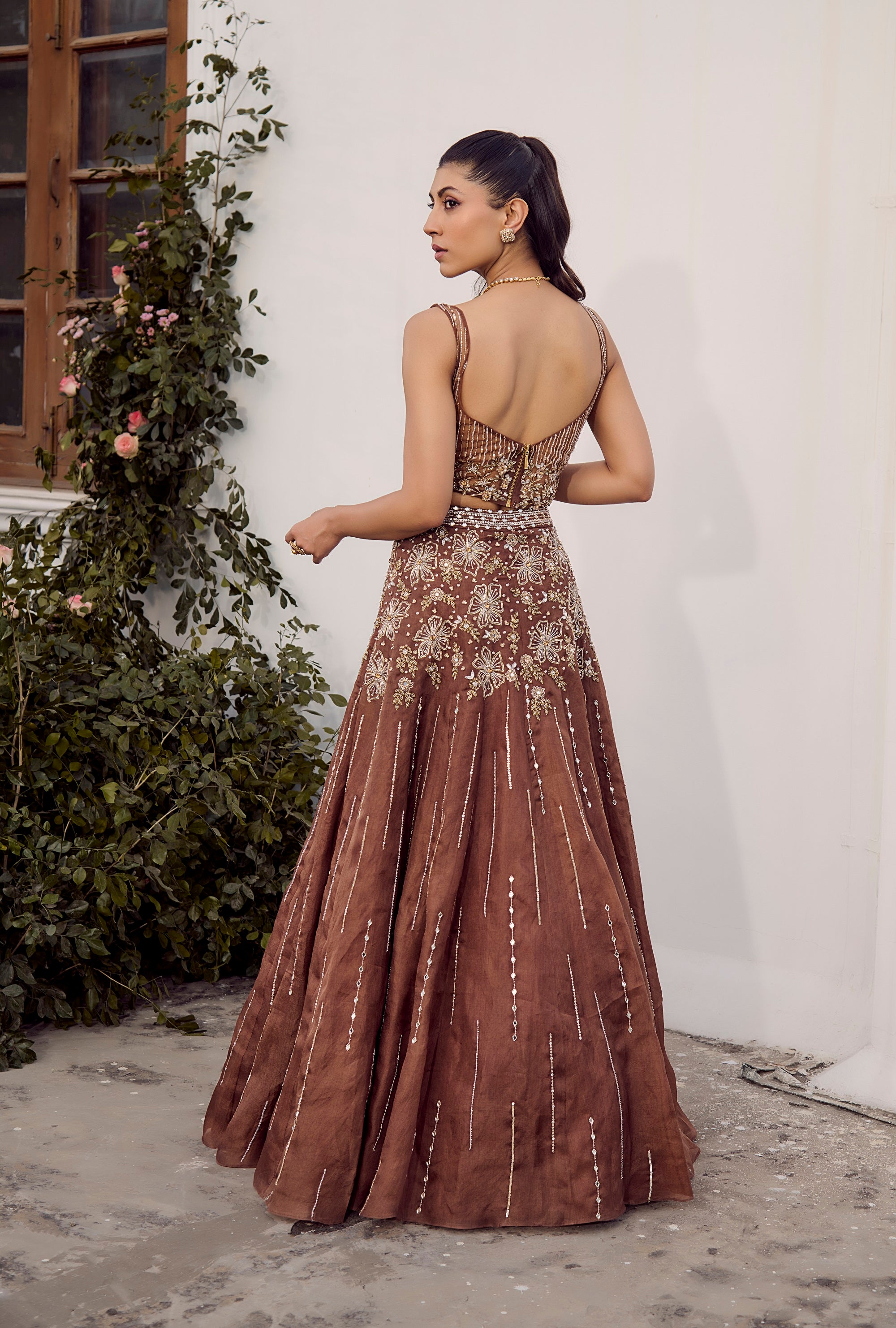 Dust Allure Lehenga Set. Woman in a brown evening gown with open back.