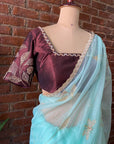 Ice Blue Organza Embroidered Saree - A maroon blouse with gold embroidery and a light blue saree