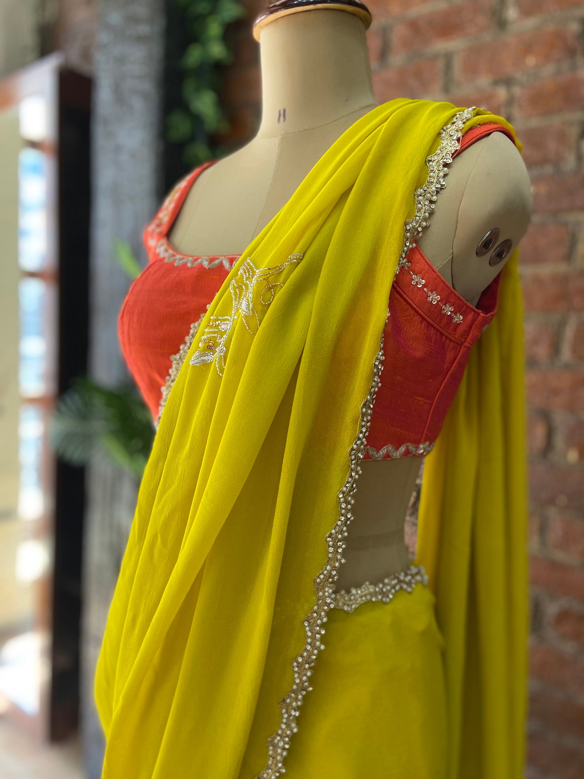 Mustard Georgette Embroidered Saree. Mannequin wearing a bright yellow saree with a red blouse