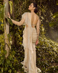 Serene Ruffle Saree. Woman in a white saree standing among green foliage